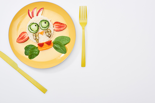 top view of plate with fancy animal made of food for childrens breakfast near cutlery on white background