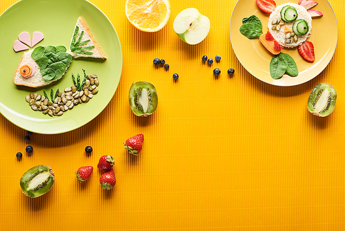 top view of plates with fancy fish and cow made of food on colorful orange background