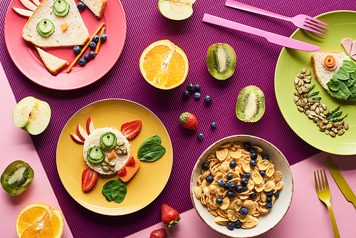 top view of plates with fancy animals made of food near fruits and breakfast cereal on purple background