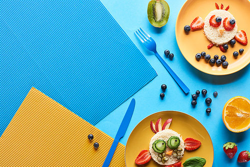 top view of plates with fancy animals made of food on blue and yellow background