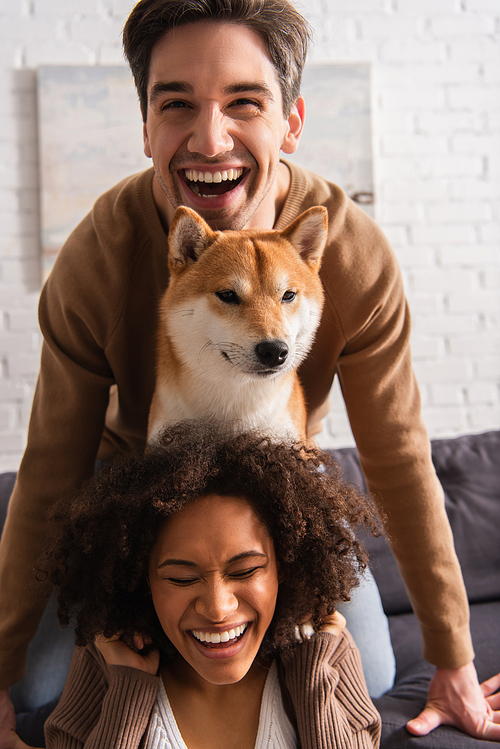 Happy man  near shiba inu and smiling african american girlfriend at home