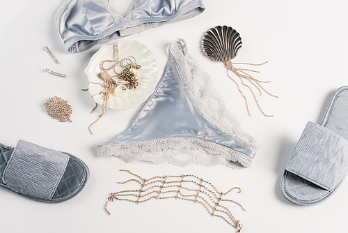 Top view of blue lingerie, slippers and accessories on white background