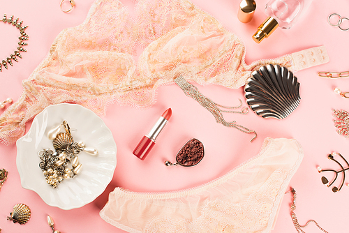 Top view of lipstick near accessories, lingerie and perfume on pink background