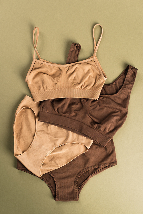 Top view of beige and brown cotton underwear on green background