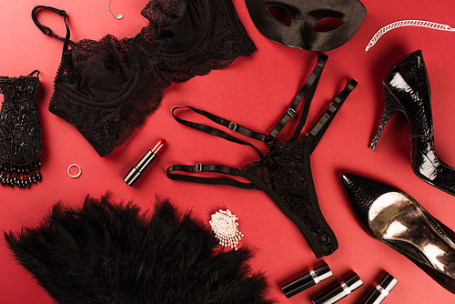 Top view of sexy lingerie, lipsticks and heels on red background
