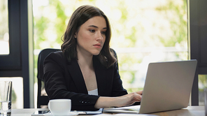 concentrated businesswoman typing on laptop at workplace