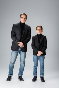 Father and son in jackets and eyeglasses  on grey background