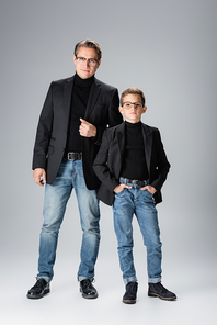 Full length of stylish father and son posing on grey background