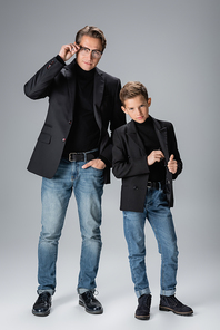Full length of trendy dad and son posing on grey background