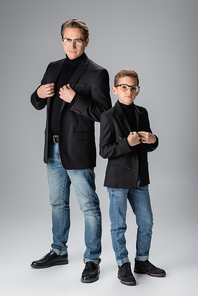 Full length of trendy dad and boy posing on grey background