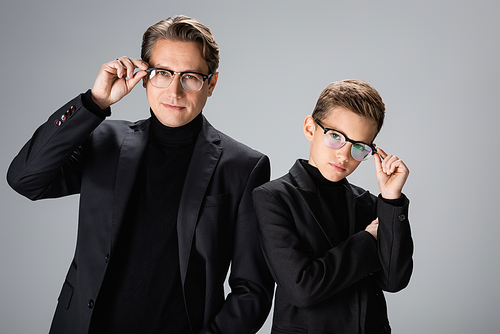 Father and boy in jackets holding eyeglasses isolated on grey
