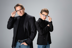 Fashionable dad and son holding eyeglasses isolated on grey
