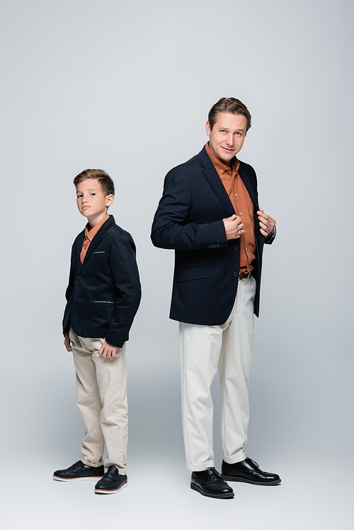 Full length of stylish boy and father  on grey background