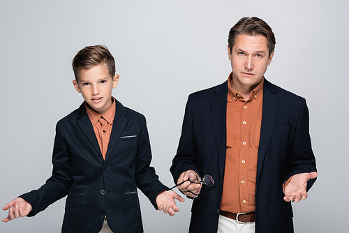 Serious father and boy in jackets  isolated on grey