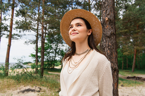 cheerful young woman in sun hat smiling in forest