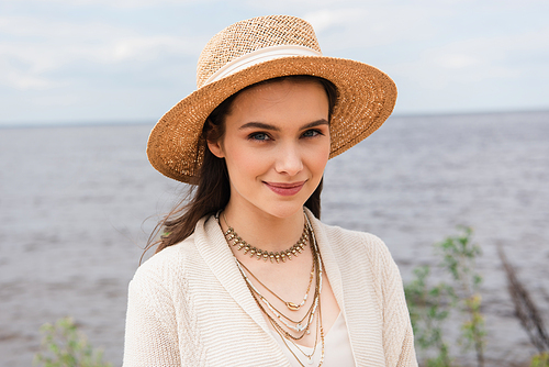 pleased young woman in sun hat  near sea