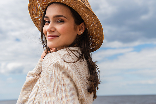 pleased young woman in sun hat against blue sky