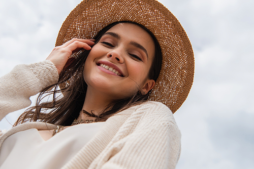 low angle view of joyful young woman in straw hat 