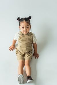 high angle view of asian toddler kid posing while sitting on grey
