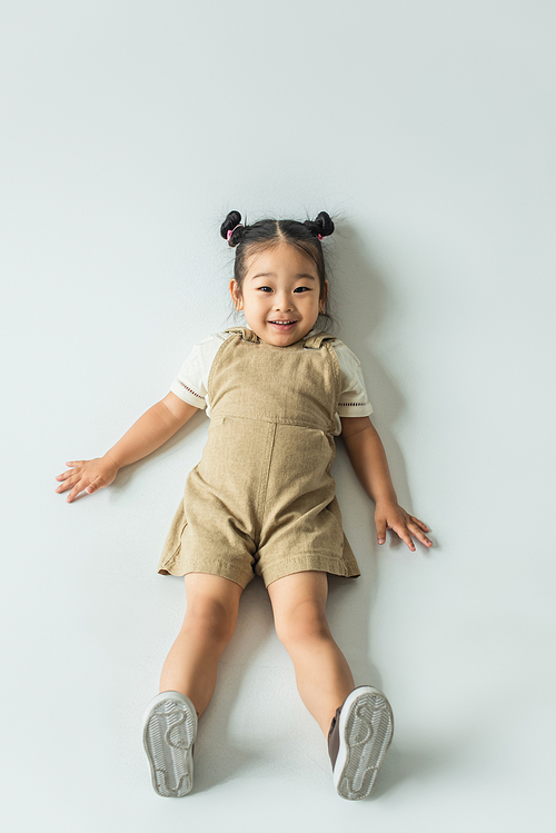 high angle view of happy asian toddler girl lying on grey