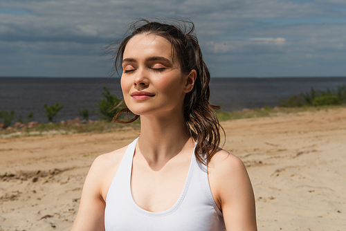 brunette and young woman with closed eyes meditating outside