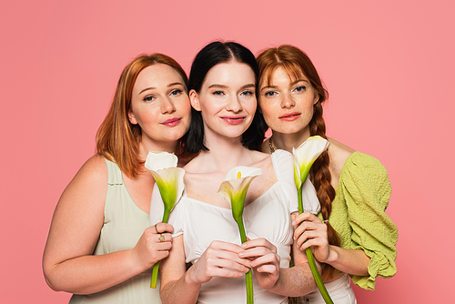 Woman with vitiligo holding calla lily near friends isolated on pink
