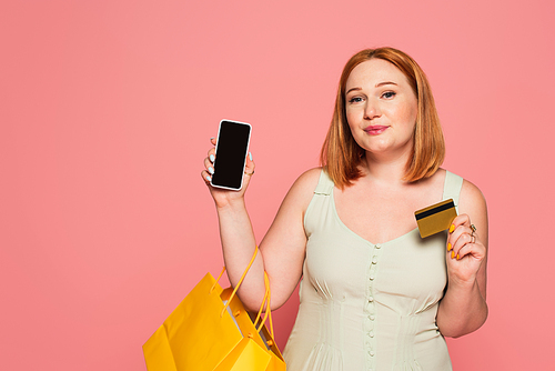 Body positive woman with shopping bags, smartphone and credit card isolated on pink
