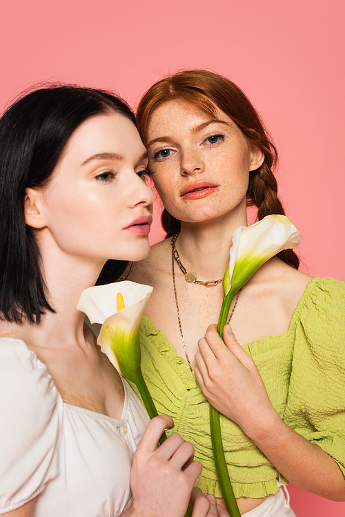 Young body positive women with flowers posing isolated on pink