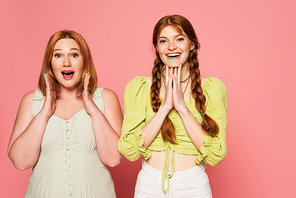 Excited plus size and freckled friends  isolated on pink