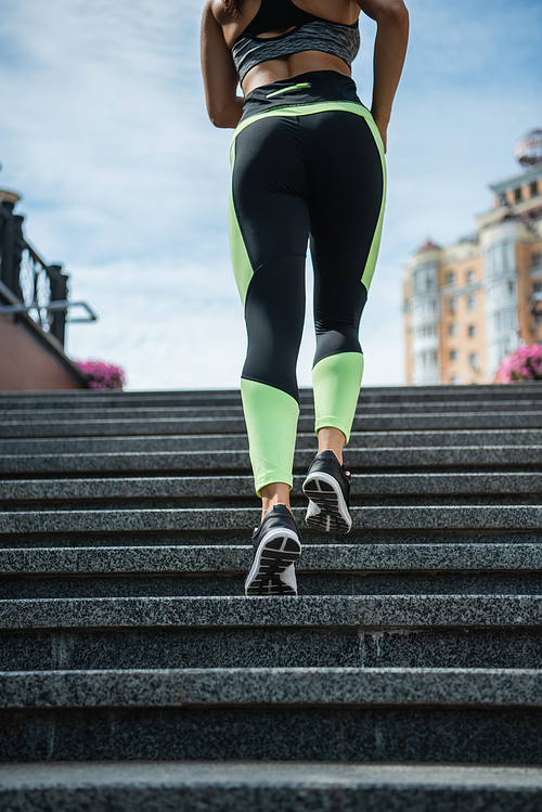 cropped view of sportive woman running on stairs outside