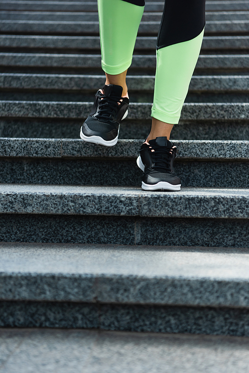 partial view of sportive woman running on stairs outside