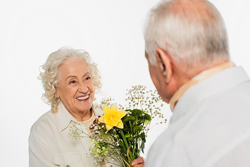 elderly man presenting bouquet of flowers to smiling wife isolated on white