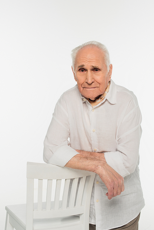 upset elderly man in casual clothes standing near stool and  isolated on white