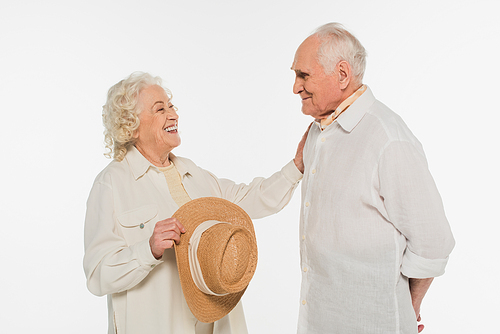 positive elderly woman holding hat and touching husband with outstretched hand isolated on white