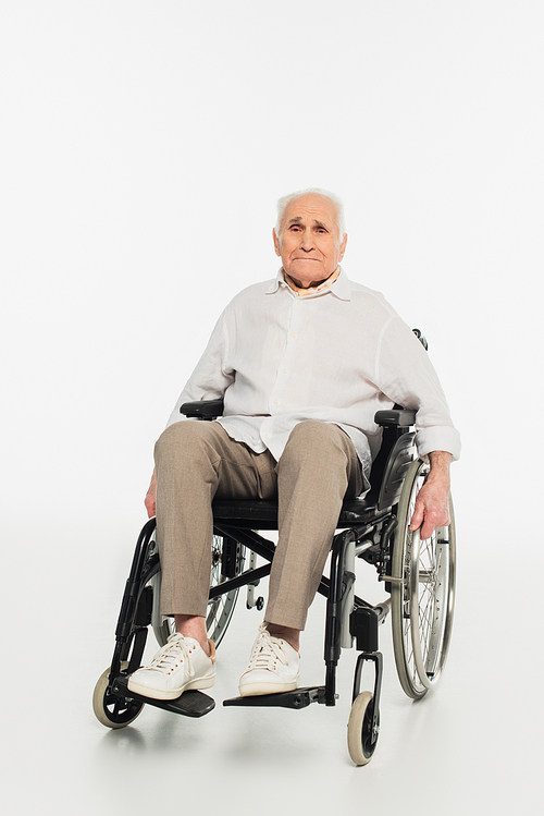 exhausted elderly man in casual clothes sitting in wheelchair on white