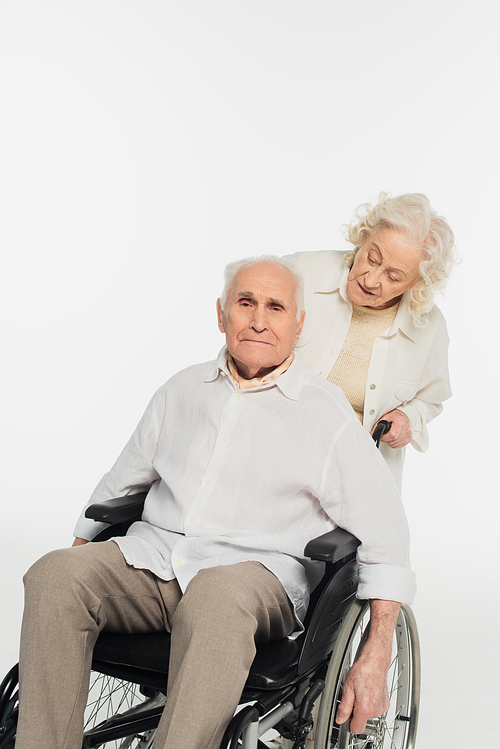 elderly woman rolling wheelchair with husband on white