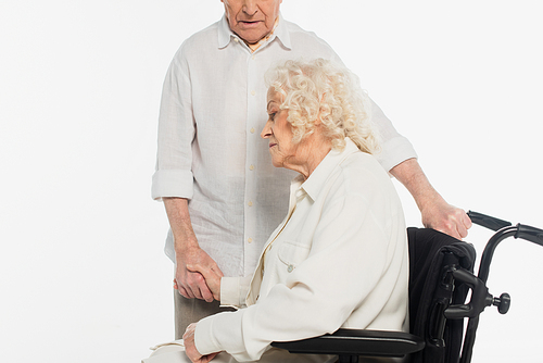 elderly woman in wheelchair holding hand of husband isolated on white