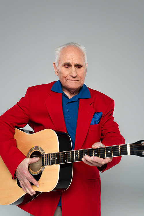 elderly man in red blazer holding acoustic guitar isolated on grey