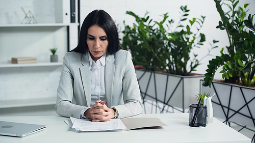 displeased businesswoman breathing and looking at documents in office