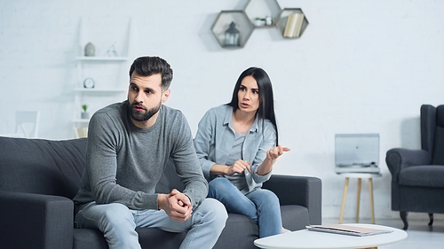 displeased woman quarreling with sad man in living room