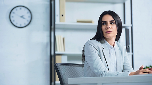 displeased businesswoman looking away while sitting at desk