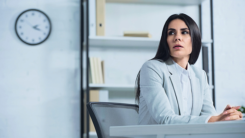 worried businesswoman looking away while sitting at desk