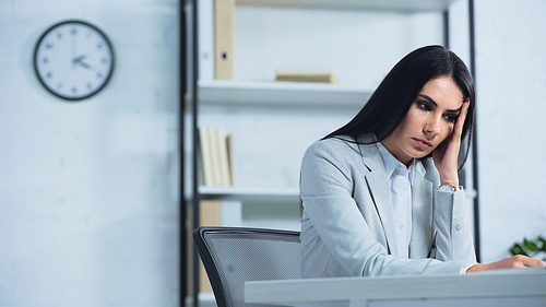 upset businesswoman looking away while sitting at desk