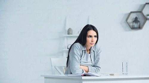 worried woman looking away while sitting at desk in office