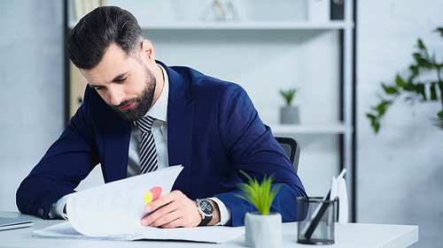 depressed businessman in suit looking at documents in office
