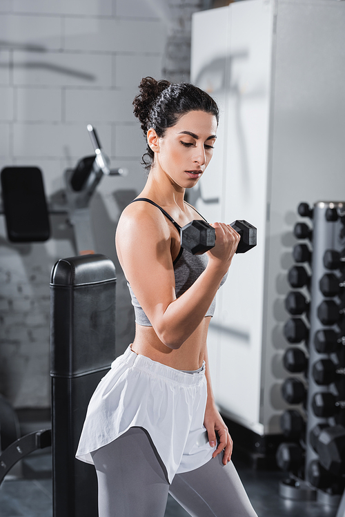 Middle east sportswoman working out with dumbbell in gym