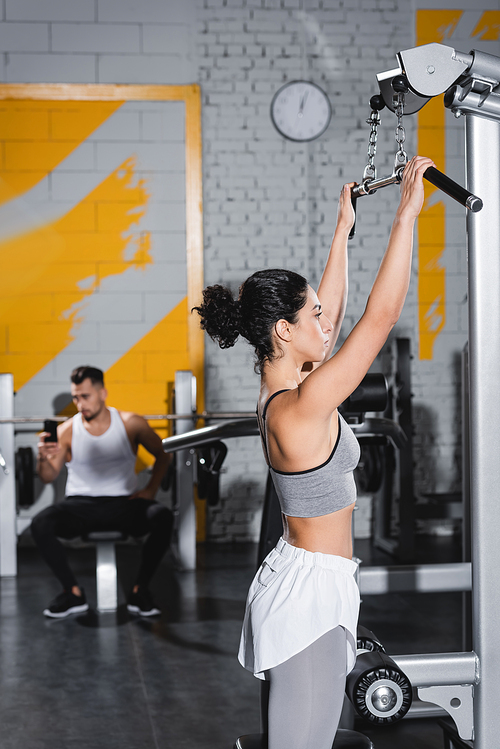 Middle east woman training on lat pulldown machine in gym