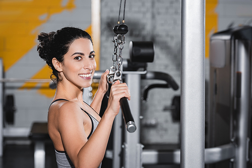 Cheerful middle east sportswoman  near lat pulldown machine in gym