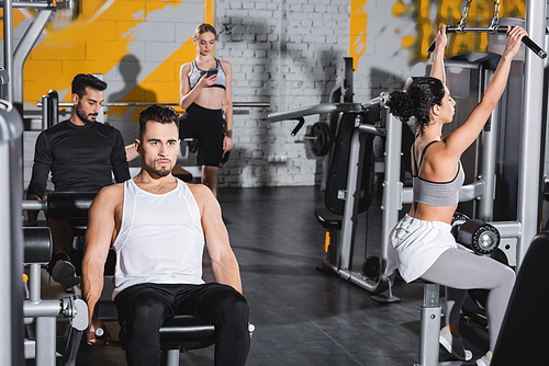 Interracial young people working out with equipment in sports center