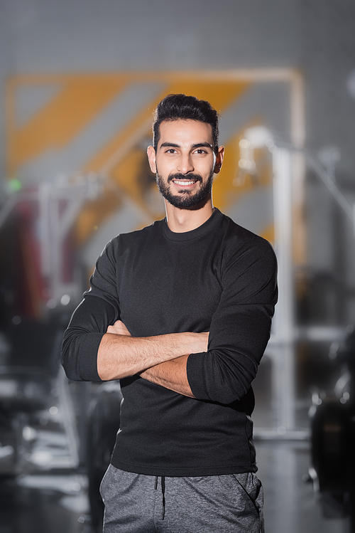 Young arabian sportsman smiling at camera in blurred gym